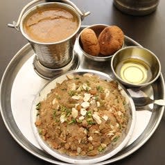 Dal baati and churma served on a steel plate and in steel bowls with a side of ghee