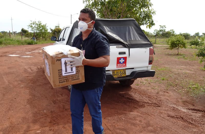 A man wearing a face mask carries a box with a test for the coronavirus disease (COVID-19), in Cumaribo