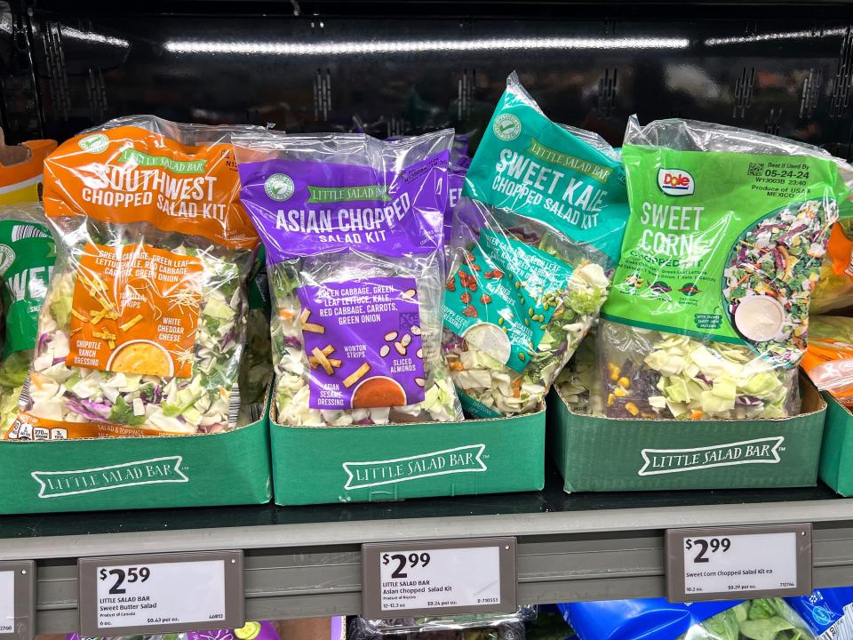 Bags of different salad kits on a shelf at Aldi.