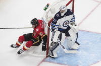 Winnipeg Jets goalie Connor Hellebuyck (37) looks for the puck as Calgary Flames' Matthew Tkachuk (19) fall into the net during the third period of an NHL hockey playoff game Saturday, Aug. 1, 2020 in Edmonton, Alberta. (Jason Franson/The Canadian Press via AP)