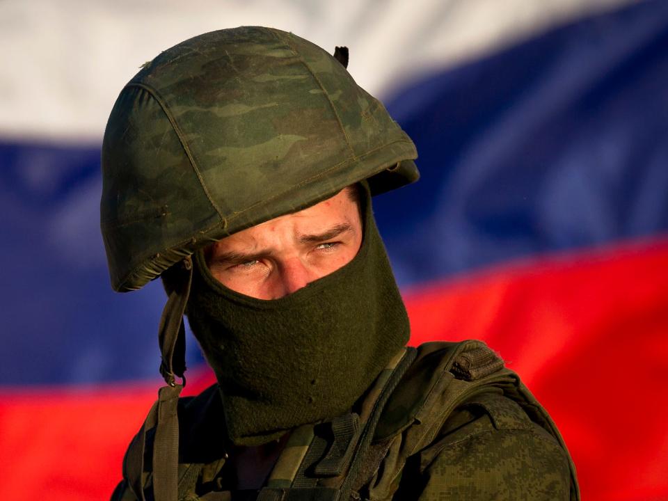 A pro-Russian soldier is back dropped by Russia's flag while manning a machine-gun outside an Ukrainian military base in Perevalne, Ukraine.