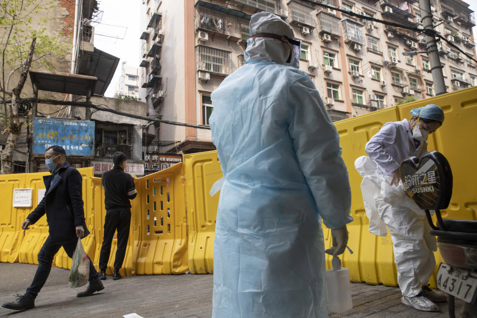 A health worker prepares to take off her protective clothing after administering tests for the coronavirus in Wuhan in central China's Hubei province on Friday, April 3, 2020. Sidewalk vendors wearing face masks and gloves sold pork, tomatoes, carrots and other vegetables to shoppers Friday in the Chinese city where the coronavirus pandemic began as workers prepared for a national memorial this weekend for health workers and others who died in the outbreak. (AP Photo/Ng Han Guan)