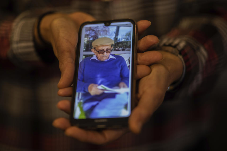 In this Monday, May 18, 2020 photo, Elena Valero shows a picture of her father Alonso Valero, 96, in Madrid, Spain. Alonso Valero was one of the residents at the Usera Center for the Elderly, who died during the coronavirus outbreak in Spain. This month, dozens of relatives of those who died in 15 Madrid nursing homes, sued the regional government and the directors of their respective nursing homes, accusing them of reckless homicide, degrading treatment, abuse of power and denial of help. Several plaintiffs were families who had loved-ones in Usera, including Elena Valero, whose father died of COVID-19 and whose mother recovered from it. (AP Photo/Bernat Armangue)