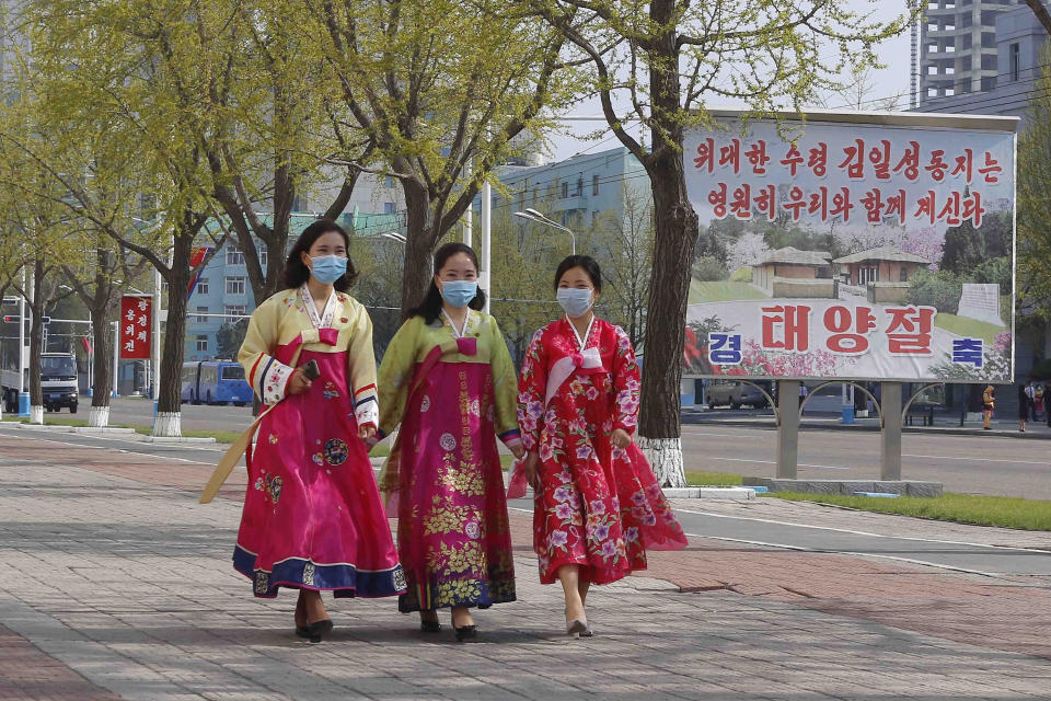 Women walk in a street near the Arch of Triumph on the Day of the Sun, the birth anniversary of late leader Kim Il Sung, in Pyongyang, North Korea Thursday, April 15, 2021. The poster reads "The great leader Comrade Kim Il Sung will always be with us. Day of the Sun." (AP Photo/Cha Song Ho)