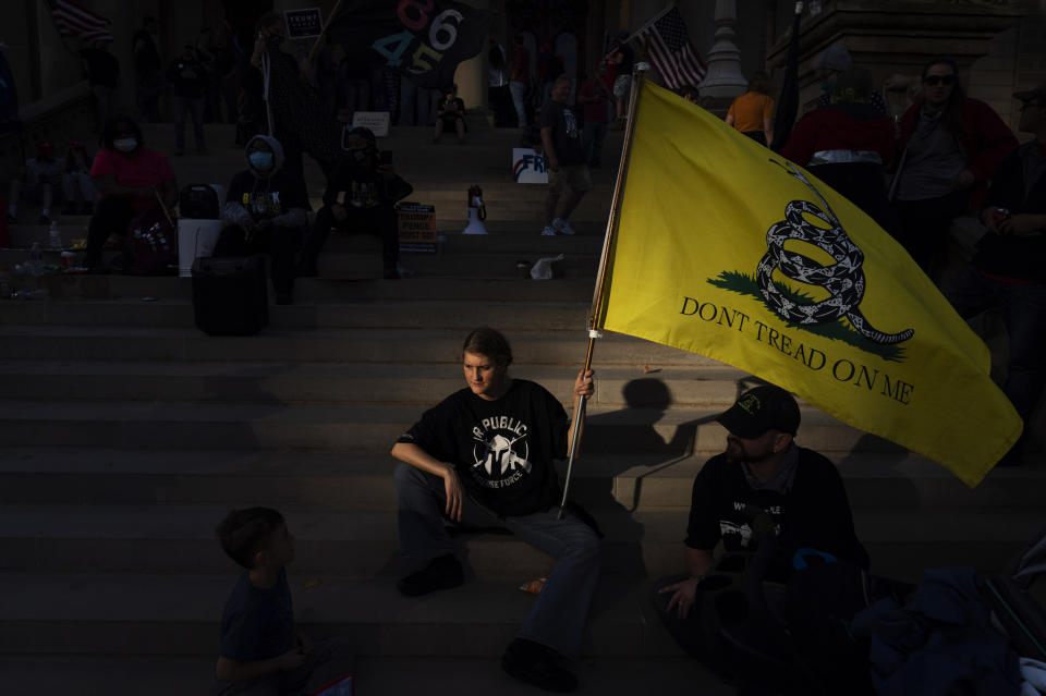 FILE - In this Nov. 8, 2020, file photo, a Donald Trump who would only give her first name, Dianna, sits on the steps of the State Capitol with her family as a protest against the presidential election results winds down in Lansing, Mich. While the state has swung back to Democrats since Trump's narrow 2016 win, choosing President Joe Biden by more than 150,000 votes, Michigan's Republican Party has taken a hard right turn. Its own Capitol in Lansing was the rallying point in April for armed Michigan Liberty Militia protesting pandemic restrictions, including some members who were later charged with plotting to kidnap Democratic Gov. Gretchen Whitmer. (AP Photo/David Goldman, File)