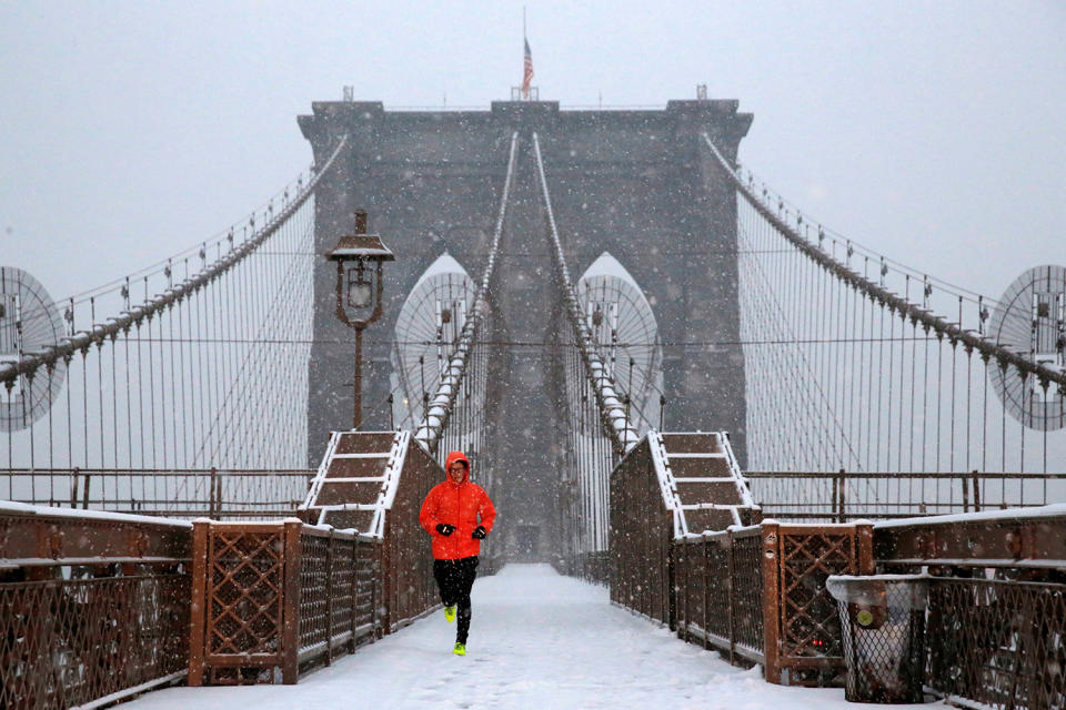 A man runs over the Brooklyn Bridge during morning snow