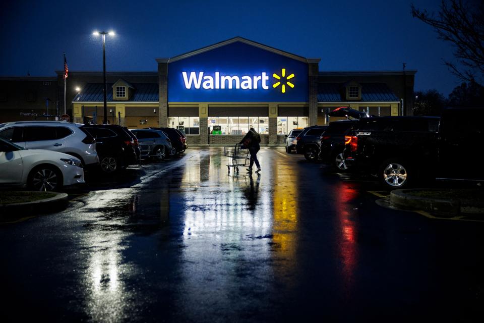 A shopper pushes a cart through the parking lot of a Walmart.