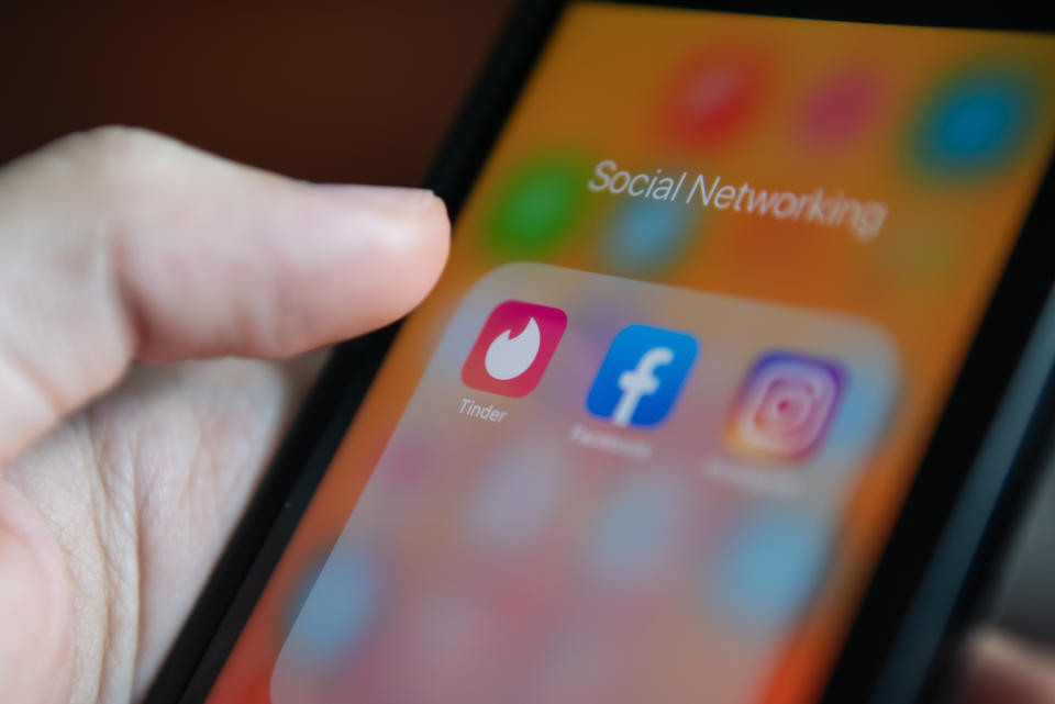 Bangkok, Thailand - July 22, 2019 : iPhone user touching Tinder logo on iPhone screen to open the app.