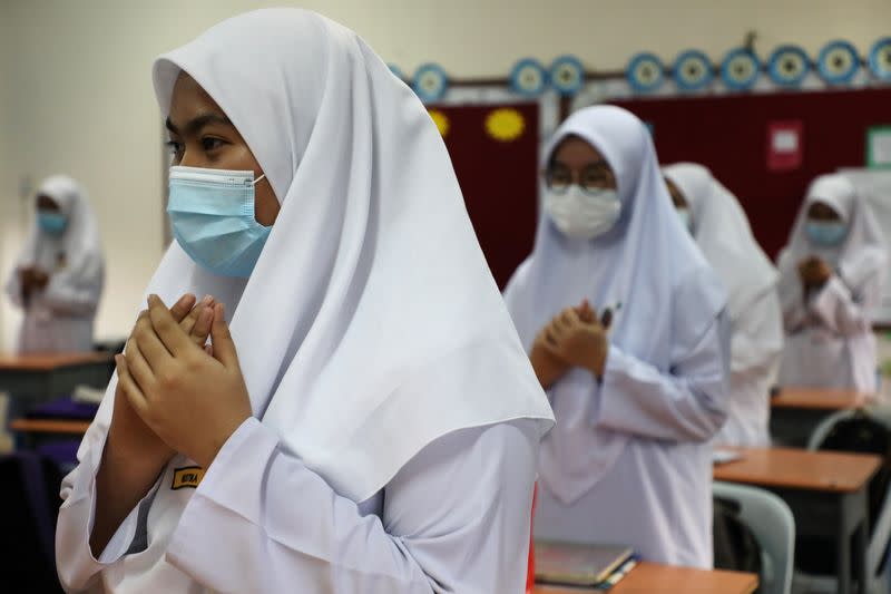 Students wearing protective masks pray before a class at a secondary school, as schools reopen amid the coronavirus disease (COVID-19) outbreak, in Shah Alam