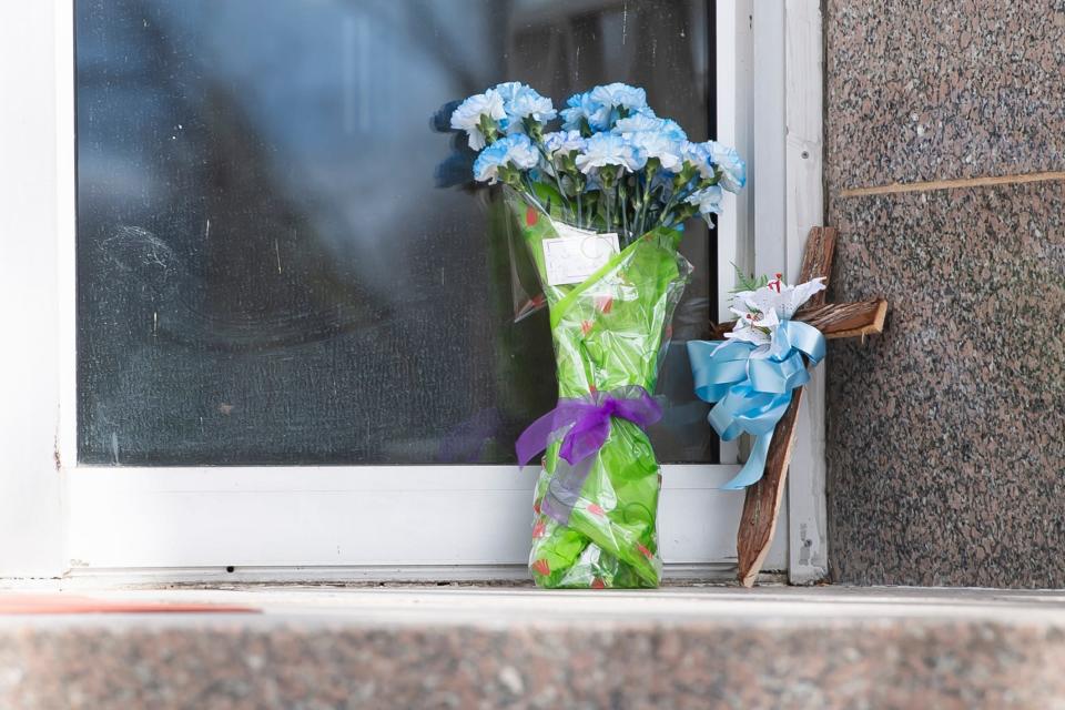 A flower bouquet and a cross sit outside an entrance to the Lebanon City Police Department on Friday, April 1, 2022.