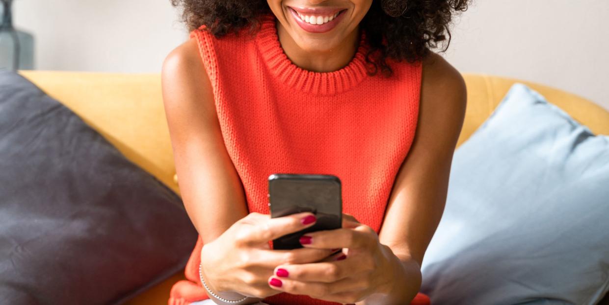 woman on couch smiling at smartphone