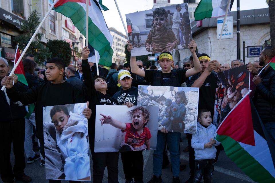 Demonstrators carry posters with pictures of Palestinians killed during the current conflict in Gaza and fly Palestinian flags during a rally in solidarity with Gaza, in the West Bank city of Ramallah, Monday, Dec. 11, 2023.