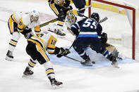 Pittsburgh Penguins goaltender Tristan Jarry (35) makes a save on Winnipeg Jets' Mark Scheifele (55) as Mike Matheson (5) and Zach Aston-Reese (12) defend during the second period of an NHL hockey game Monday, Nov. 22, 2021, in Winnipeg, Manitoba. (Fred Greenslade/The Canadian Press via AP)
