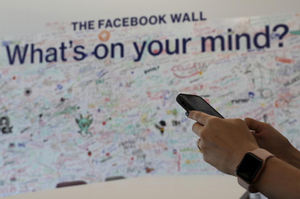 In this Monday, May 20, 2019 photo, a woman uses her mobile at the Facebook office in Dubai, United Arab Emirates. The Muslim holy month of Ramadan, with its long days of fasting and prayer meant to draw worshippers closer to God and away from worldly distractions, is being reshaped by technology. People in the Middle East are spending close to 58 million more hours on Facebook and watching more YouTube videos than at any other time of the year, making Ramadan the biggest moment of the year for advertisers. (AP Photo/Kamran Jebreili)