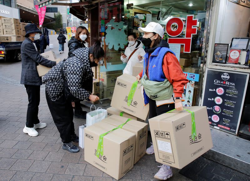 Tourists leave after buying masks to prevent contracting coronavirus, at a pharmacy in the Myeong-dong in Seoul