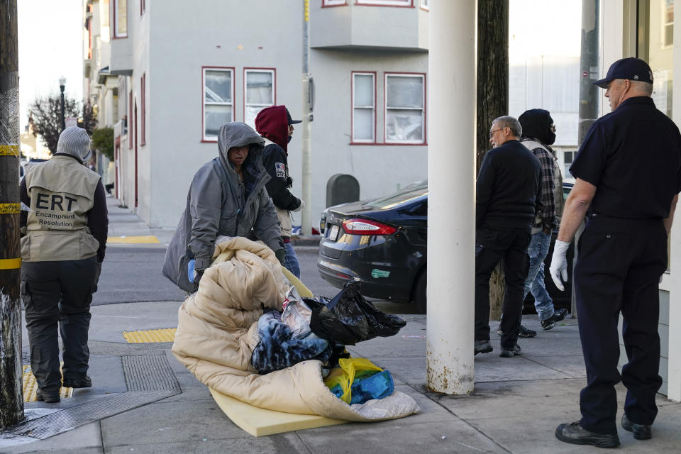 A homeless woman moves her belongings after being approached by the San Francisco Homeless Outreach Team's Encampment Resolution Team in San Francisco, Tuesday, Dec. 13, 2022. (AP Photo/Godofredo A. Vásquez)