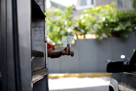 An employee of the state oil company PDVSA's gas station shows a Venezuelan bolivar note at his work place in Caracas, Venezuela May 17 2019. REUTERS/Ivan Alvarado