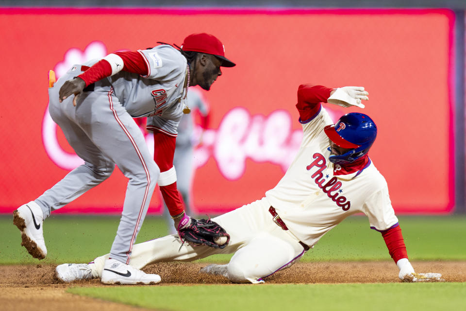 Cincinnati Reds shortstop Elly De La Cruz, left, tags out Philadelphia Phillies' Nick Castellanos on a steal attempt during the second inning of a baseball game Wednesday, April 3, 2024, in Philadelphia. (AP Photo/Chris Szagola)