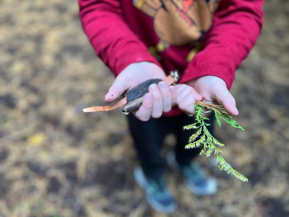 A Grade 3 student in Millbrook, Ont., shows off plant material gathered from around the outdoor learning space in the forest next to their elementary school.