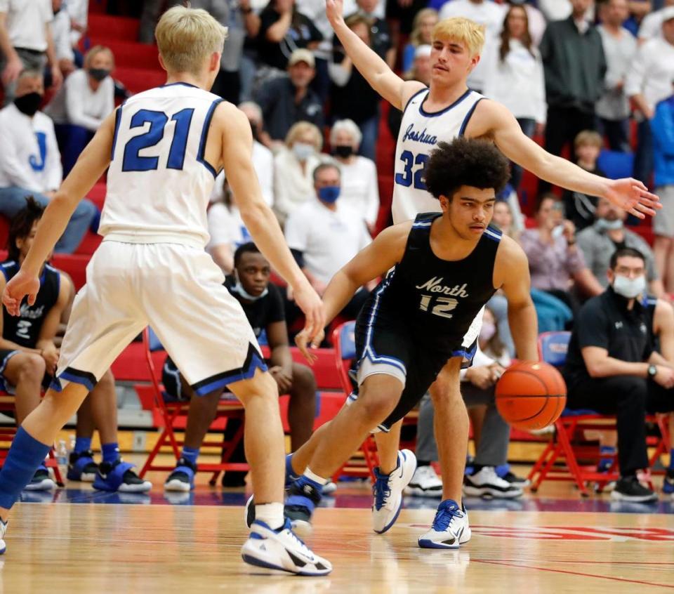 North Forney guard Deshaun Brundage (12) breaks between the defense of Joshua guard Logan Rice (21) and center Noah Smith (32) during the second half of a 5A region 2 bi-district basketball game at Grapevine High School in Grapevine, Texas, Tuesday, Feb. 23, 2021. North Forney defeated Joshua 61-50. (Special to the Star-Telegram Bob Booth)