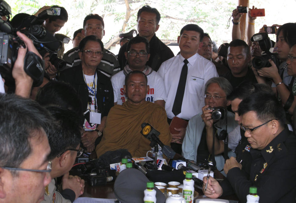 In this photo taken Monday, Jan. 27, 2014, local monk protest leader Luang Pu Buddha Issara, center, listens to high level police officers asking him to leave the neighboring government building to Bangkok, Thailand. Some government officials have resorted to pleading with protests occupying their government offices where daily functions such as passport controls and immigration issues are backing up. It was an extraordinarily humbling moment for Prime Minister Yingluck Shinawatra's embattled administration, which ascended to power following a landslide election two and a half years ago. (AP Photo/Thanyarat Doksone)