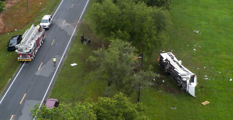 Emergency services attend the scene after a bus carrying laborers to a melon farm overturned in a fatal crash near Dunnellon