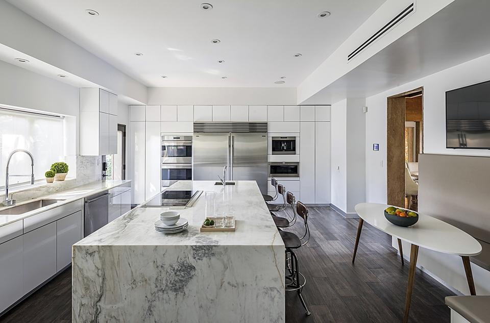 Large modern kitchen with large center island with chairs and stainless steel mega fridge