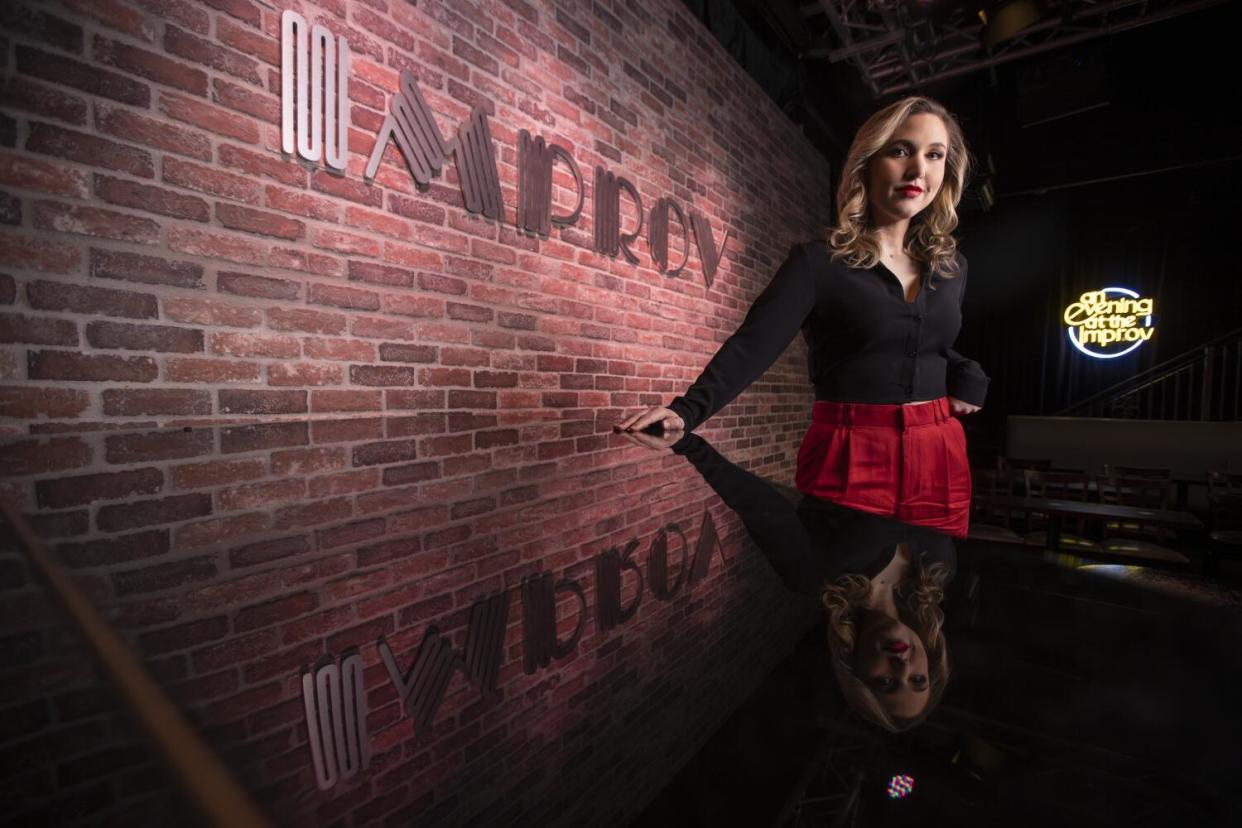 Woman standing behind a piano and in front of a brick wall