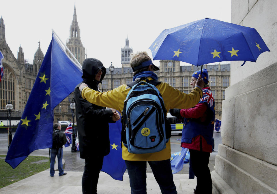 Remain supporters shelter from the wind and rain across the street from parliament in London, Thursday Feb. 28, 2019. British Prime Minister Theresa May has offered Parliament the chance to delay Britain's scheduled March 29 departure if lawmakers fail to approve her divorce agreement with the bloc.(Jonathan Brady/PA via AP)