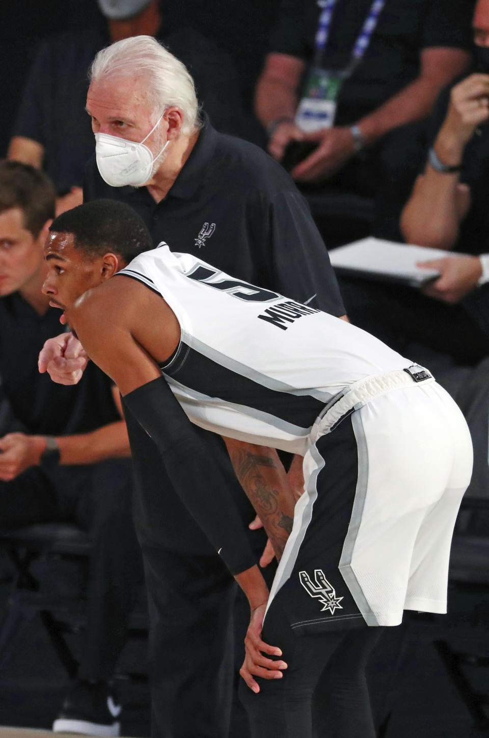 San Antonio Spurs head coach Gregg Popovich in a mask talks with guard Dejounte Murray (5) during the first half of an NBA basketball game, Friday, July 31, 2020, in Lake Buena Vista, Fla. (Kim Klement/Pool Photo via AP)