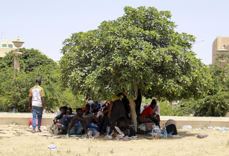 Migrants shade under a tree during a gathering in Sfax, Tunisia's eastern coast, Friday, July 7, 2023. Tensions spiked dangerously in a Tunisian port city this week after three migrants were detained in the death of a local man, and there were reports of retaliation against Black foreigners and accounts of mass expulsions and alleged assaults by security forces. (AP Photo)