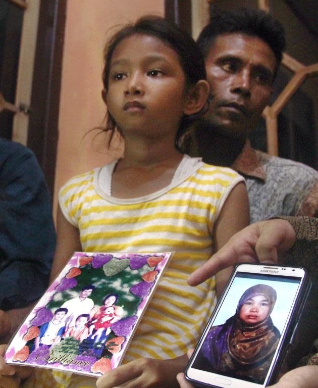 Desi Sri Rahayu, the ten-year-old daughter of Karni Binti Medi Tarsim, an Indonesian domestic worker executed in Saudi Arabia, holds a family potrait as she sits with her father Darpin at their home in Brebes in central Java on April 17, 2015