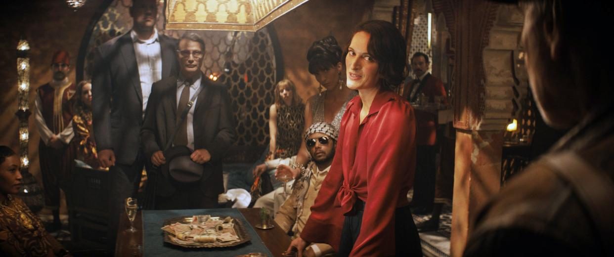 NDIANA JONES AND THE DIAL OF DESTINY, (aka INDIANA JONES 5), Mads Mikkelsen (center), Phoebe Waller-Bridge (red blouse), Harrison Ford (right, back to camera), 2023. © Walt Disney Studios Motion Pictures / Courtesy Everett Collection