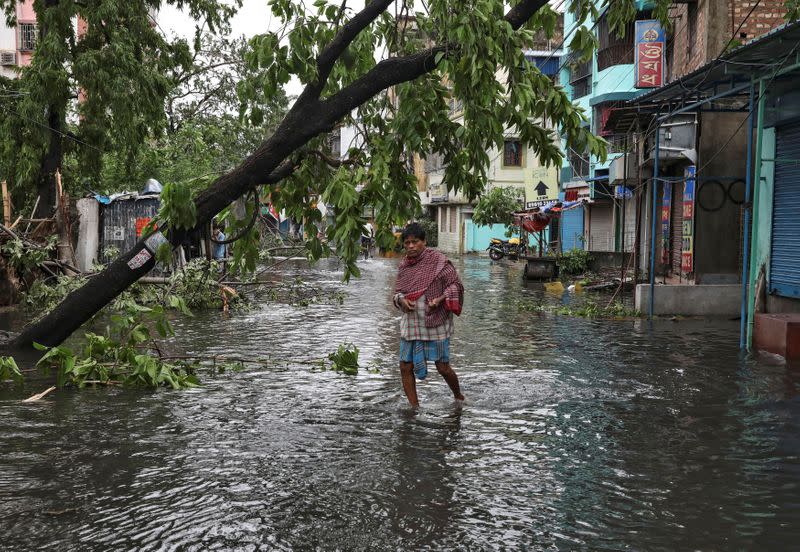 A man crosses a flooded street after Cyclone Amphan made its landfall in Kolkata