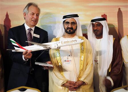 Boeing Chairman James McNerney (L) shows United Arab Emirates' Prime Minister and Ruler of Dubai Sheikh Mohammed bin Rashid al-Maktoum (2nd R) a model of the new version of its 777 long-haul jet during the Dubai Airshow November 17, 2013. REUTERS/Ahmed Jadallah