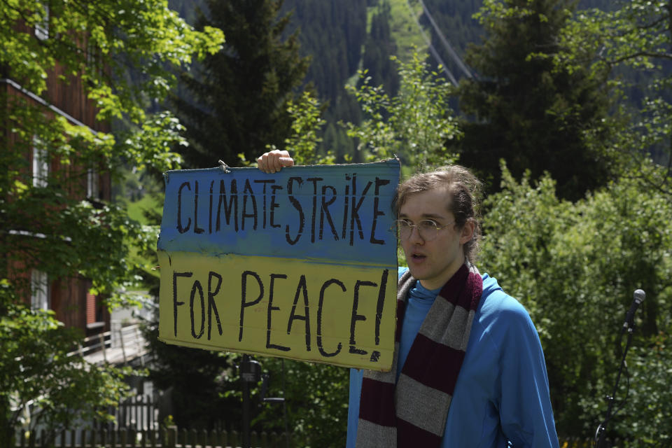 CAPTION CORRECTS THE NAME - Ilyess El Kortbi, climate activist shows a poster in colours of Ukrainian flag during a climate protest alongside the World Economic Forum in Davos, Switzerland, Thursday, May 26, 2022. The annual meeting of the World Economic Forum is taking place in Davos from May 22 until May 26, 2022. (AP Photo/Evgeniy Maloletka)