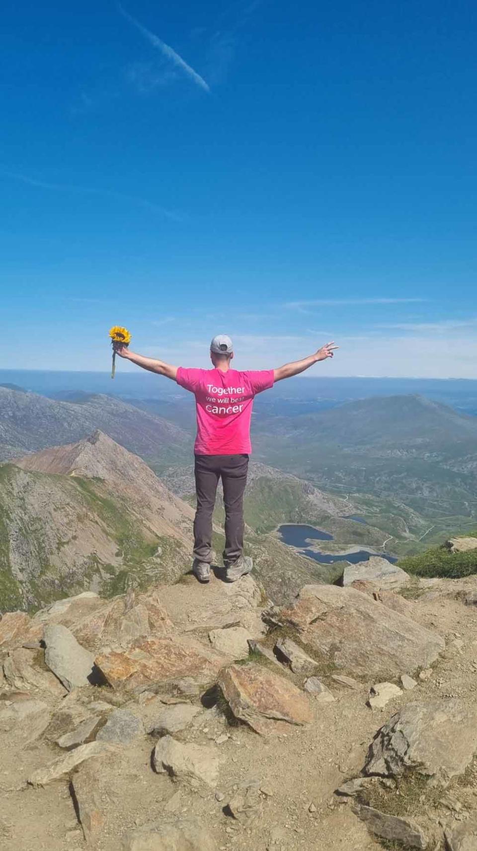 Ryan holding a sunflower at the top of Snowdon, Wales. (PA Real Life/Collect)