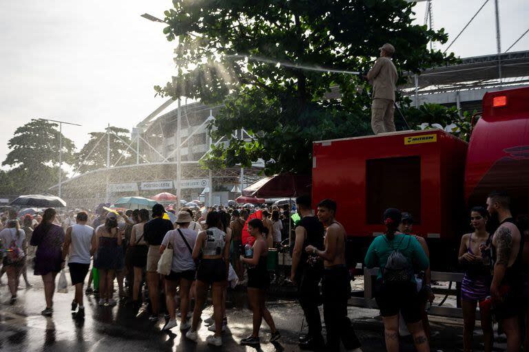 Un bombero tira agua sobre los fans de Taylor Swift en el Estadio Olímpico Nilton Santos, en Río de Janeiro. (Tercio TEIXEIRA / AFP)