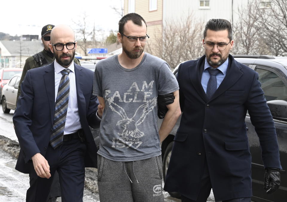 Steeve Gagnon is escorted by police into court in Amqui, Quebec, Tuesday, March 14, 2023. The 38-year-old man is facing two charges of dangerous driving causing death after after a pickup truck rammed into pedestrians. (Jacques Boissinot/The Canadian Press via AP)