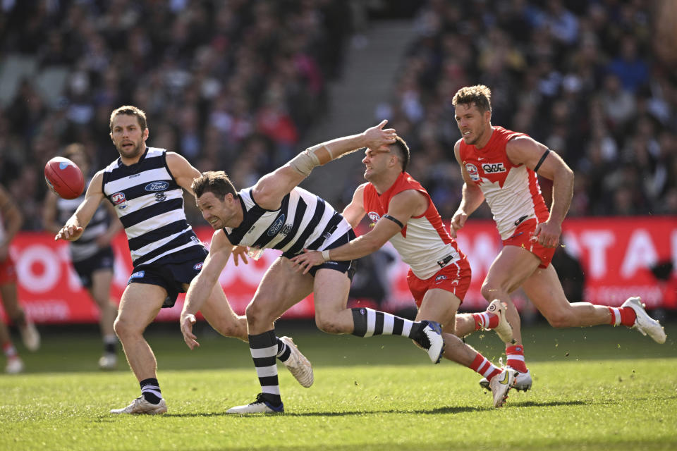 Patrick Dangerfield of Geelong, second left, is tackled by Tom Papley of the Swans during the AFL Grand Final between the Geelong Cats and the Sydney Swans at the Melbourne Cricket Ground in Melbourne, Australia, Saturday, Sept. 24, 2022. (James Ross/AAP Image via AP)