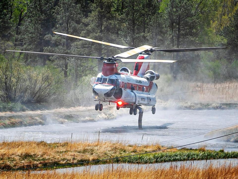 A chinook helicopter draws water from a pond along Highway 434 to drop on a nearby ridge as firefighters from all over the country converge on Northern New Mexico to battle the Hermit's Peak and Calf Canyon fires on May 13, 2022.