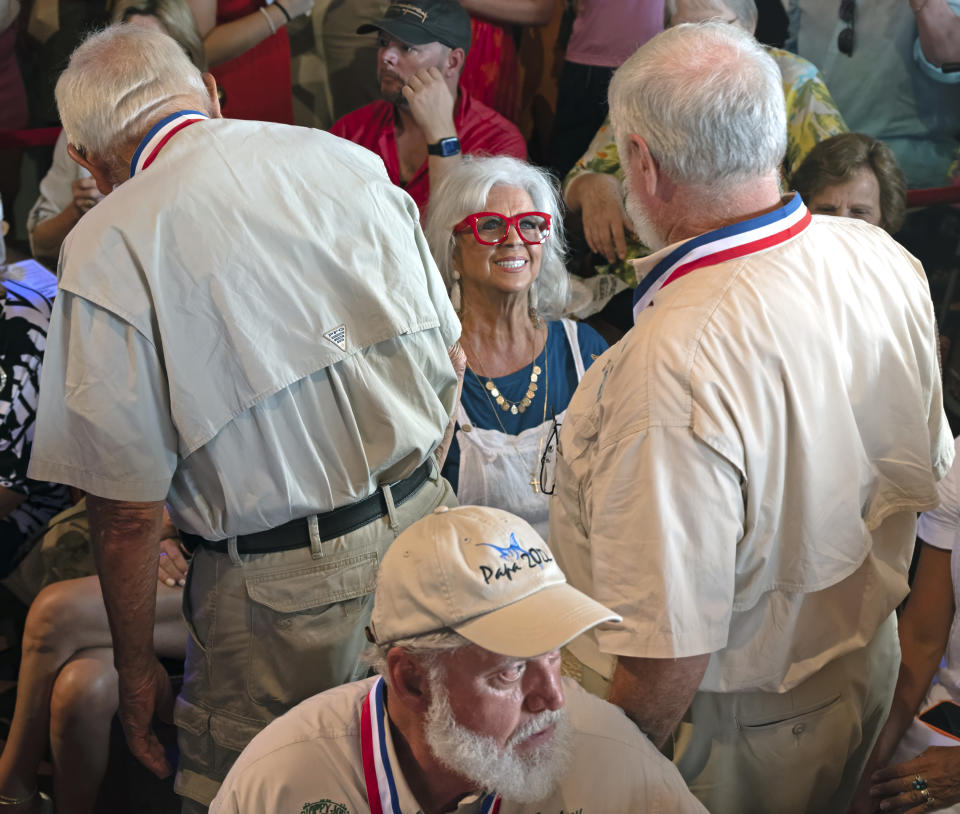 In this Saturday, July 22, 2023, photo provided by the Florida Keys News Bureau, celebrity chef Paula Deen, center, greets previous winners of the Hemingway Look-Alike Contest at Sloppy Joe's Bar in Key West, Fla. Deen's husband, Michael Groover, won the contest in 2018. At front is 2022 winner Jon Auvil. The competition was a highlight of the annual Hemingway Days festival that ends Sunday, July 23. Ernest Hemingway lived in Key West throughout most of the 1930s. (Andy Newman/Florida Keys News Bureau via AP)