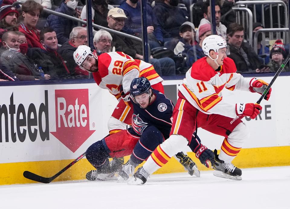 Columbus Blue Jackets defenseman Dean Kukan (46) collides with Calgary Flames center Dillon Dube (29) and center Mikael Backlund (11) during the second period of the NHL hockey game at Nationwide Arena in Columbus on Wednesday, Jan. 26, 2022. 