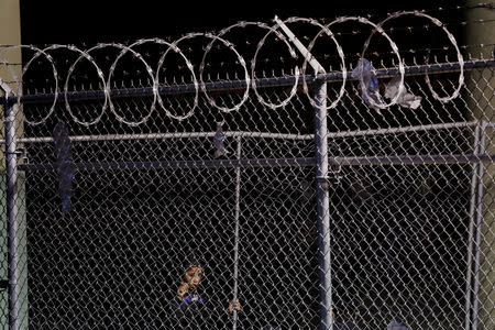 A young child looks through a fence inside an enclosure, where they are being held by U.S. Customs and Border Protection (CBP), after crossing the border between Mexico and the United States illegally and turning themselves in to request asylum, in El Paso, Texas, U.S., March 29, 2019. REUTERS/Lucas Jackson