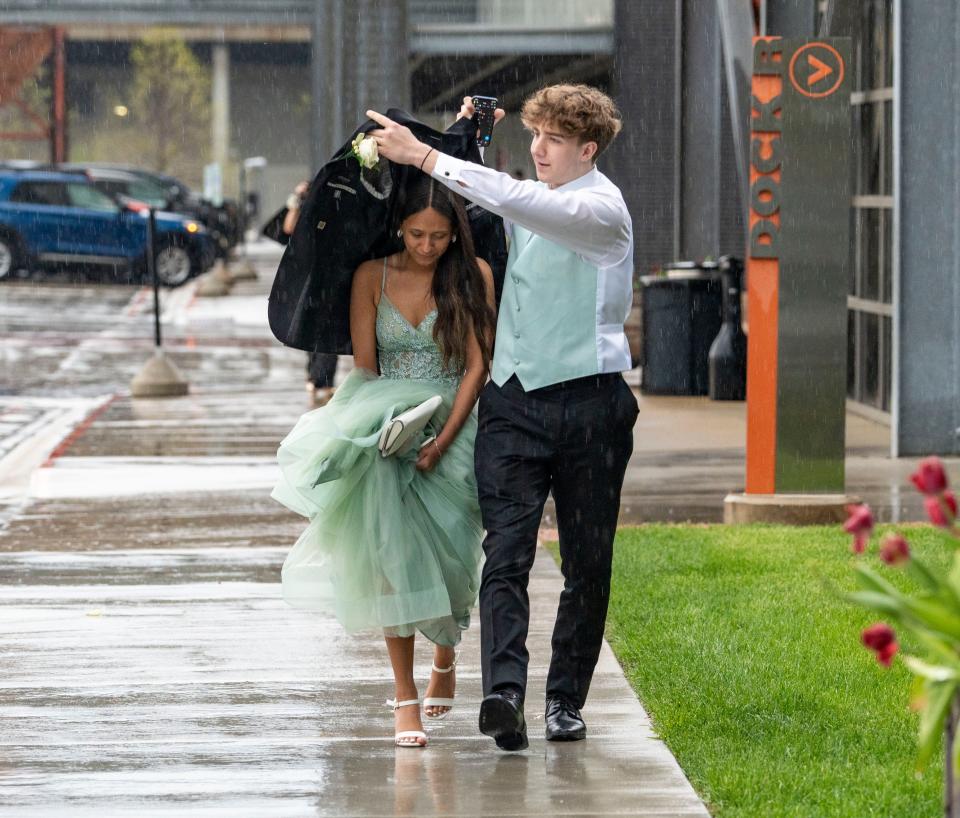Greenfield High School junior Owen Beachamp uses his blazer to cover junior Madison Reyes from the rain as they rush to enter the prom at Garage at The Harley-Davidson Museum on May 4 in Milwaukee.