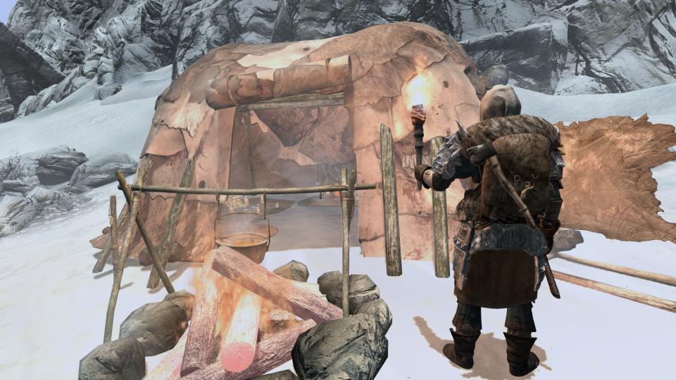 Best Skyrim mods — a torch-wielding adventurer inspects their hide tent..