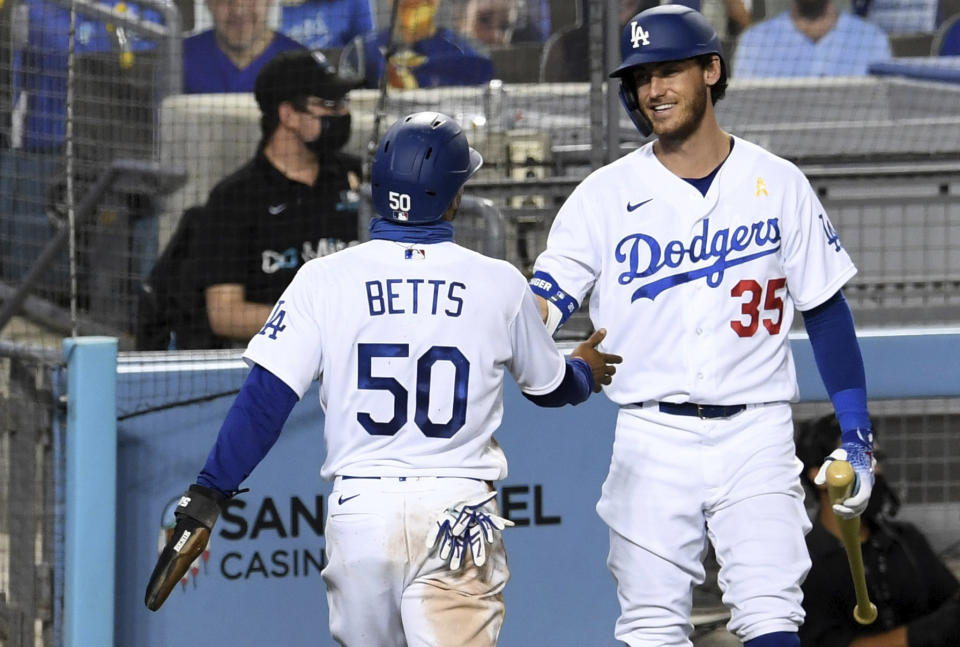 Mookie Betts (50) of the Los Angeles Dodgers reacts with teammate Cody Bellinger (35) after scoring from first base on a double by teammate Corey Seager (5) against the Colorado Rockies in the fifth inning of a MLB baseball game at Dodger Stadium in Los Angeles on Saturday, Sept. 5, 2020. (Keith Birmingham/The Orange County Register via AP)