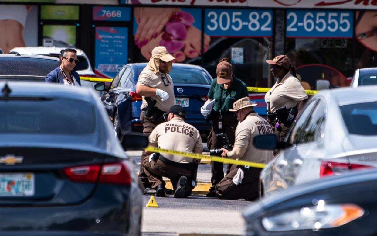 Miami Dade police officers collect evidence from the parking lot in front of a billiard's club that was rented for a concert - CHANDAN KHANNA /AFP