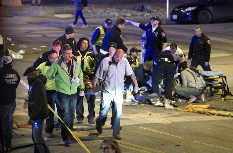 People carry a person who was struck by a car on Red River Street in downtown Austin, Texas, at SXSW on Wednesday March 12, 2014. Police say a man and woman have been killed after a suspected drunken driver fleeing from arrest crashed through barricades set up for the South By Southwest festival and struck the pair and others on a crowded street. (AP Photo/Austin American-Statesman, Jay Janner)