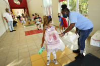 FILE - In this Aug. 6, 2020, file photo, Tannissa Jefferies, a physical education teacher at Saltillo Primary School, helps students arriving on their first day get to their proper hallway as they enter from the carpool line in Saltillo, Miss. As schools reopen around the country, their ability to quickly identify and contain coronavirus outbreaks before they get out of hand is about to be put to the test. (Adam Robison/The Northeast Mississippi Daily Journal via AP, File)